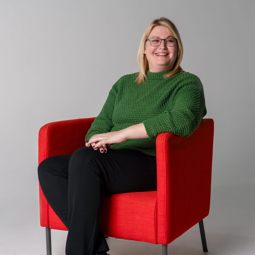Michelle Whalen smiling, seated in a red armchair